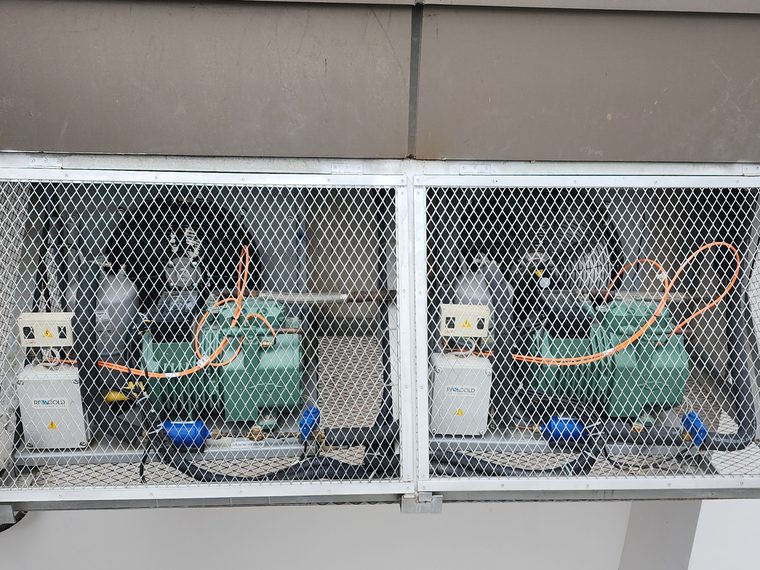 Rooftop refrigeration compressors in a caged enclosure
